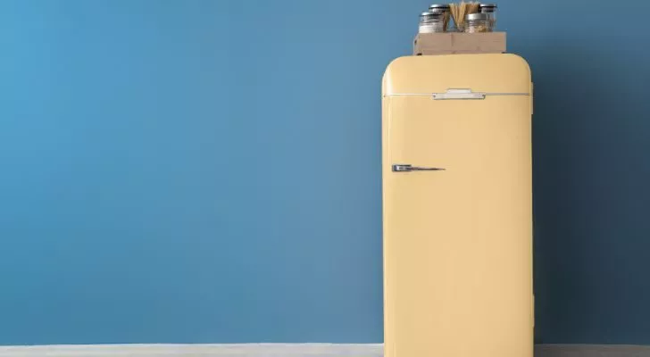 An old fashioned refrigerator standing in an empty room