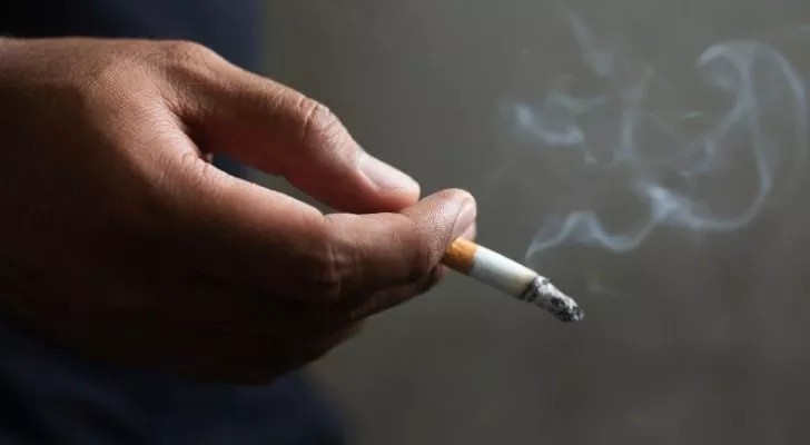 A person's hand holding a lit cigarette