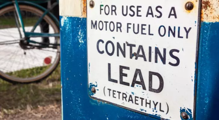 An old fueling station pump with a sign that reads "contains lead"