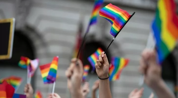 A crowd waving rainbow flags in the air
