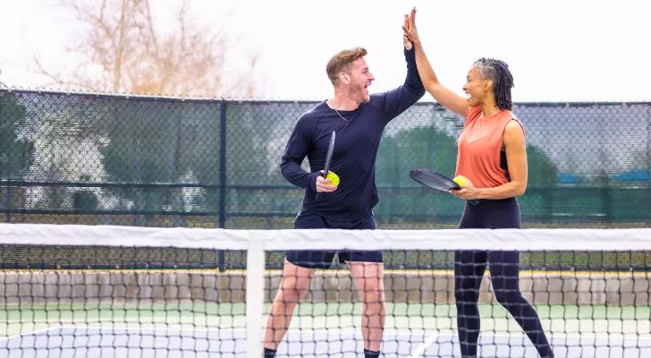 Two friends high five while playing a game of pickleball