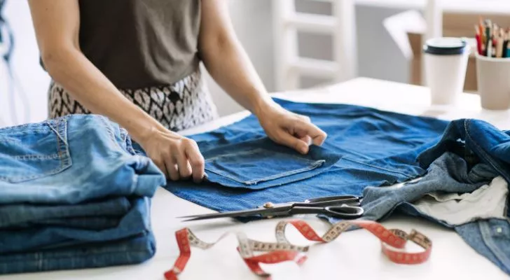 A woman using pieces of denim material to fabricate something new