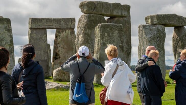 Visitors at Stonehenge observing the prehistoric monument with large stone structures on a cloudy day