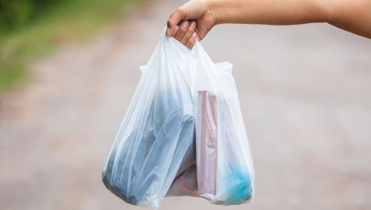 Hand holding clear plastic bags with various items inside, highlighting non-recyclable soft plastic packaging