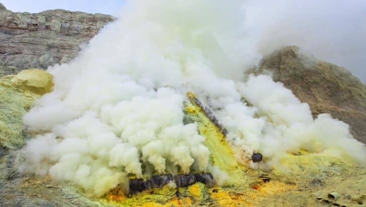 Volcanic gases emitting from fumaroles, creating clouds of smoke with yellow sulfur deposits