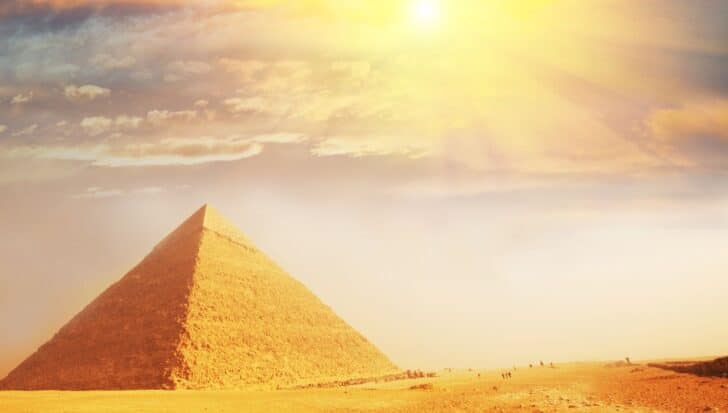 The Great Pyramid of Giza under a bright sun with a few people visible in the distance