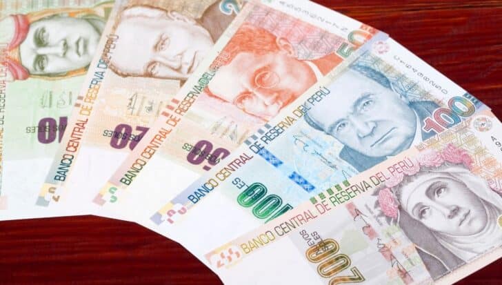 Various denominations of Peruvian banknotes displayed fanwise on a wooden surface