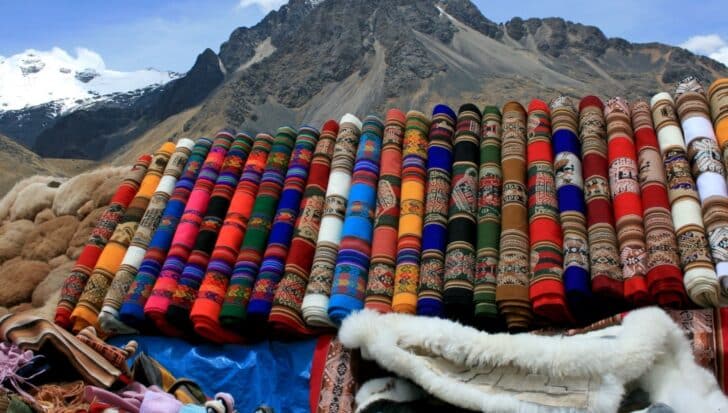 Colorful traditional Peruvian ponchos displayed in front of a mountain landscape