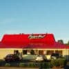 Exterior of a Pizza Hut restaurant with a red roof and several cars parked outside, displaying a sign advertising Kids Night