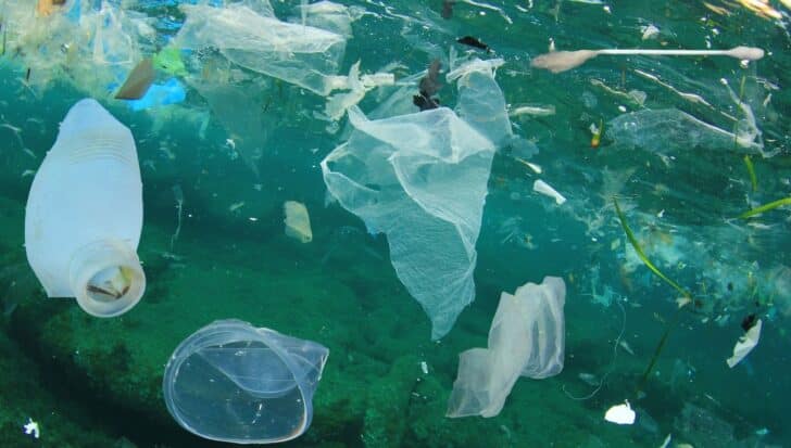 Ocean water filled with various pieces of plastic debris, including bottles and bags