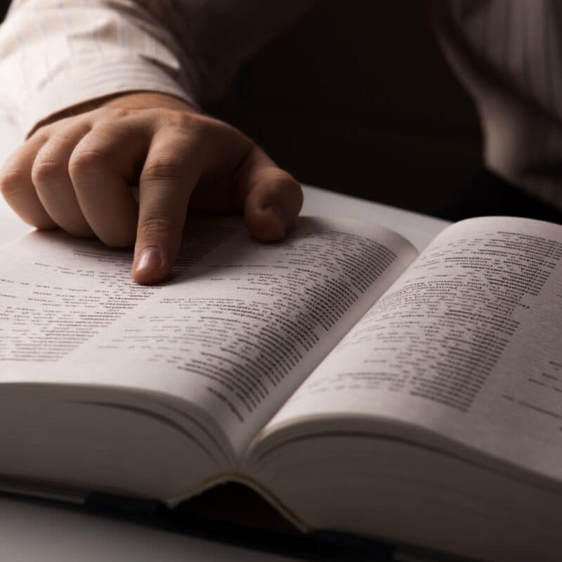 A hand pointing to text in an open dictionary