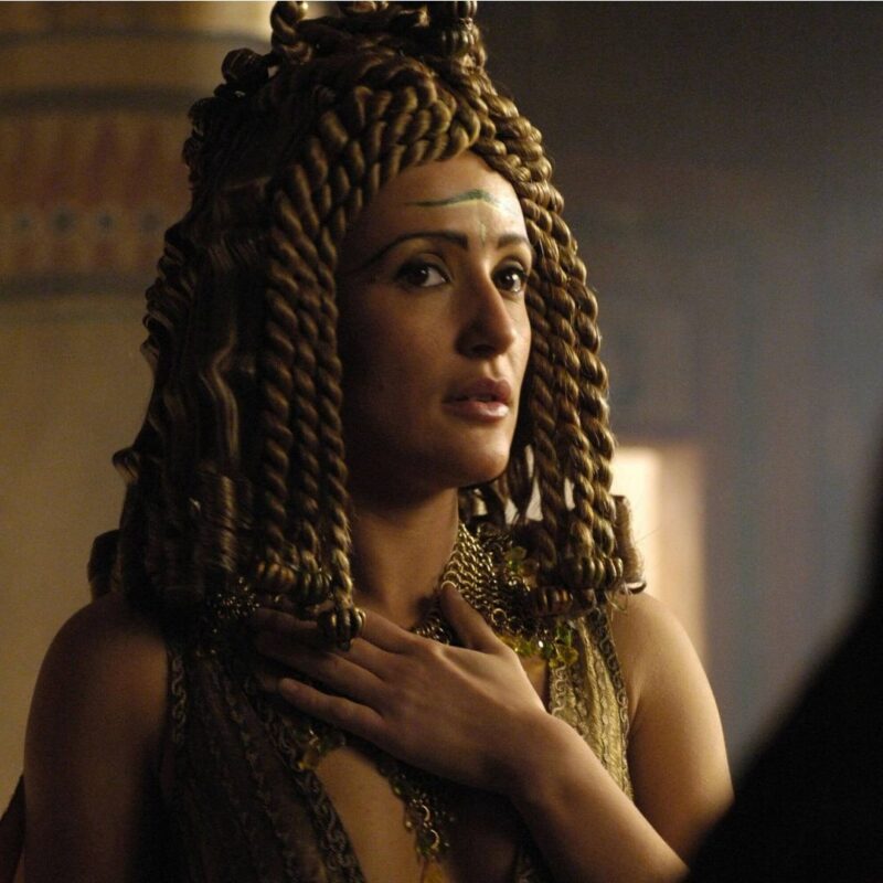 A woman with braided hair and intricate jewelry in an ancient setting