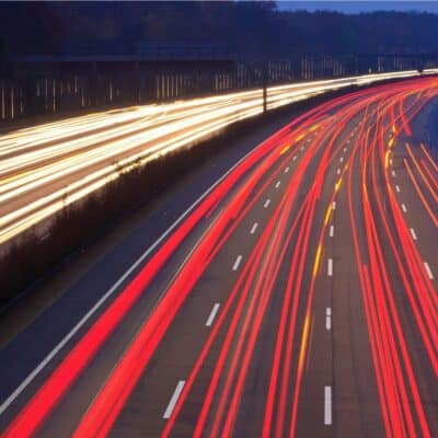High-speed traffic on a multi-lane highway at night with long-exposure light trails from vehicles