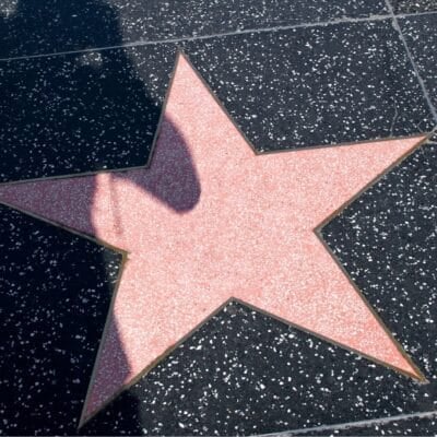 A blank pink star on the Hollywood Walk of Fame surrounded by speckled black tiles
