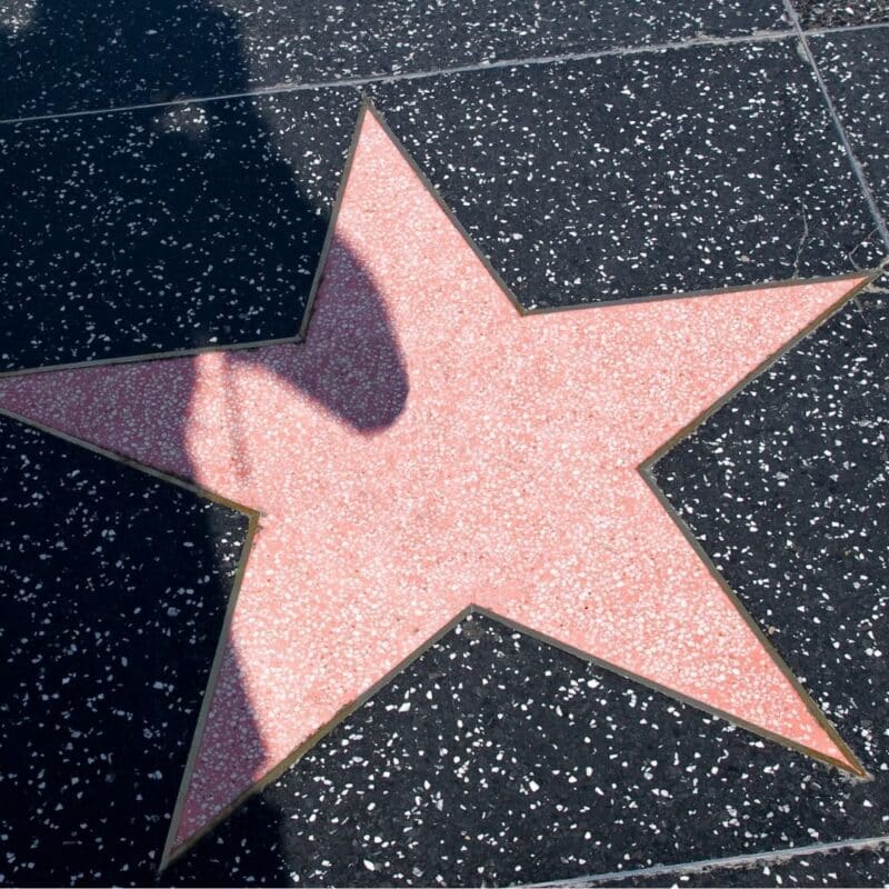 A blank pink star on the Hollywood Walk of Fame surrounded by speckled black tiles