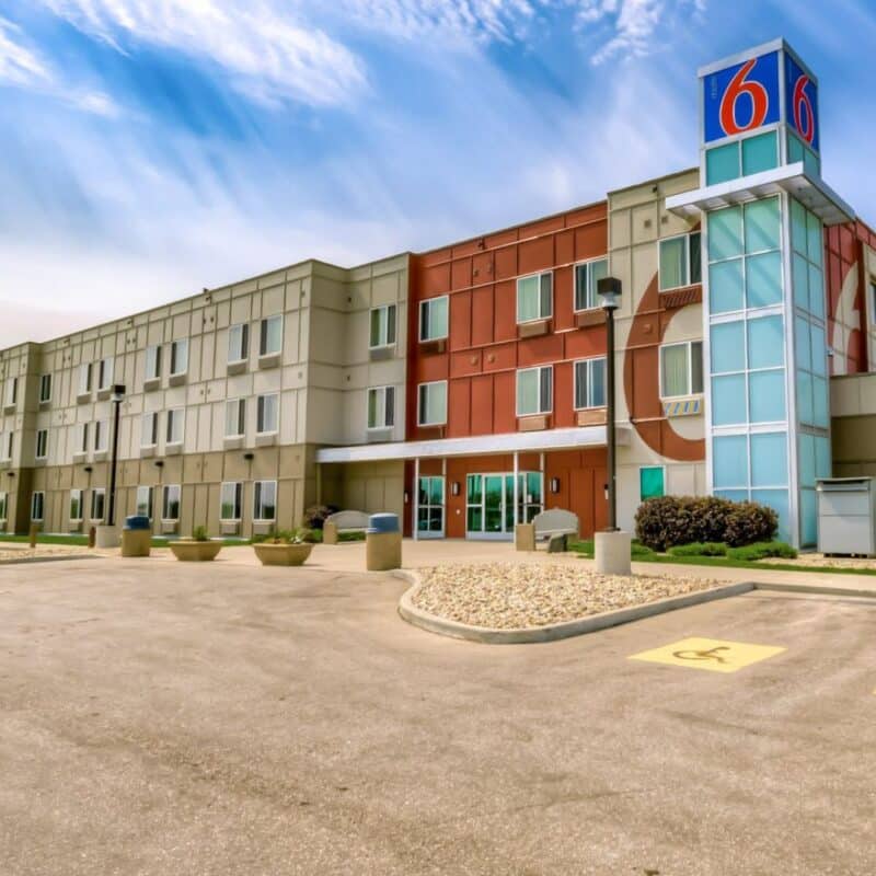 Exterior view of a Motel 6 building with a modern design and the Motel 6 logo prominently displayed on top