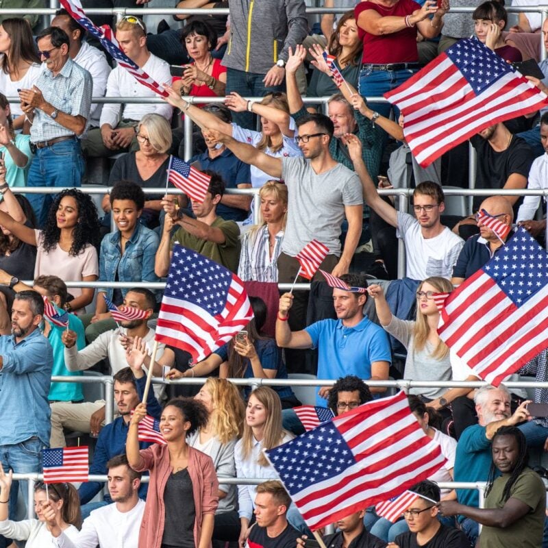 A diverse crowd enthusiastically waves American flags