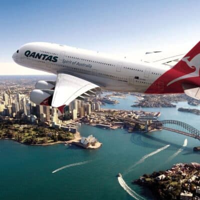 Qantas Airways aircraft flying over Sydney Harbour with the Sydney Opera House and Harbour Bridge in the background