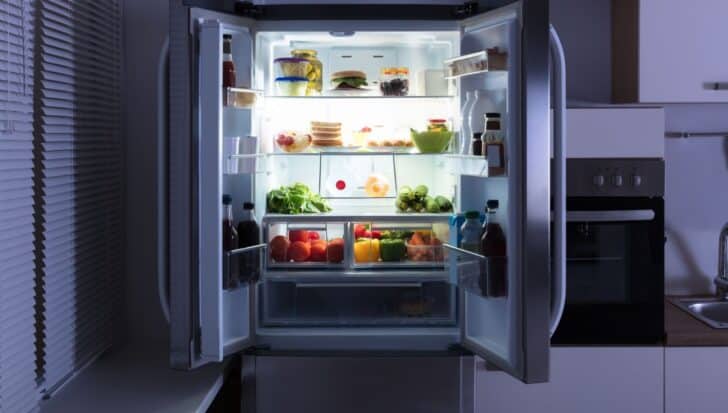 Open fridge filled with various foods and drinks, including vegetables, bottles, and dairy products