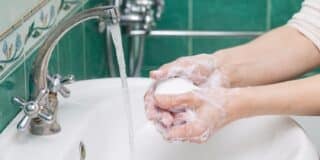 Person washing hands with a bar of soap under a running faucet