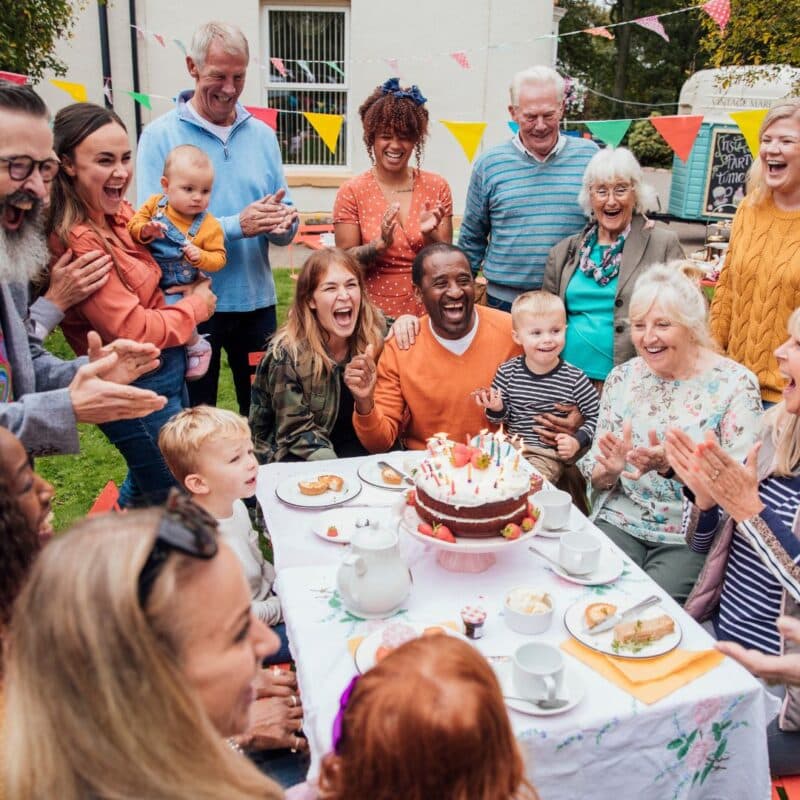 A diverse group of people celebrating a birthday outdoors