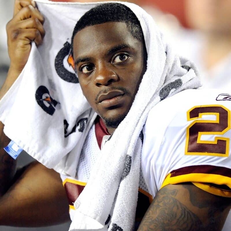 NFL player on the sidelines with a towel on his head, wearing a jersey