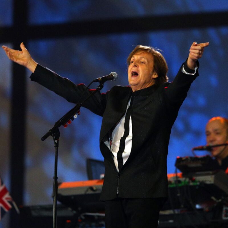 Paul McCartney performing passionately on stage at the 2012 London Olympics