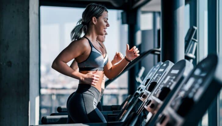 Two people running on treadmills in a modern gym, highlighting the benefits of treadmill workouts for heart health