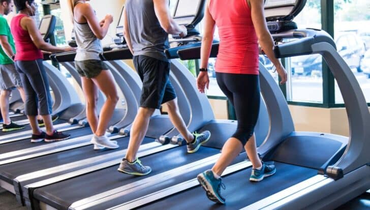 Group of people using treadmills with advanced controls for incline and speed in a gym setting