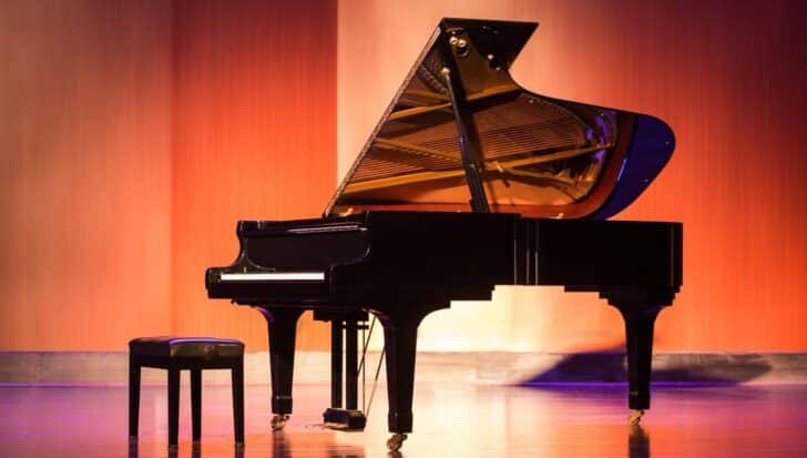Grand piano on a stage, accompanied by a piano bench