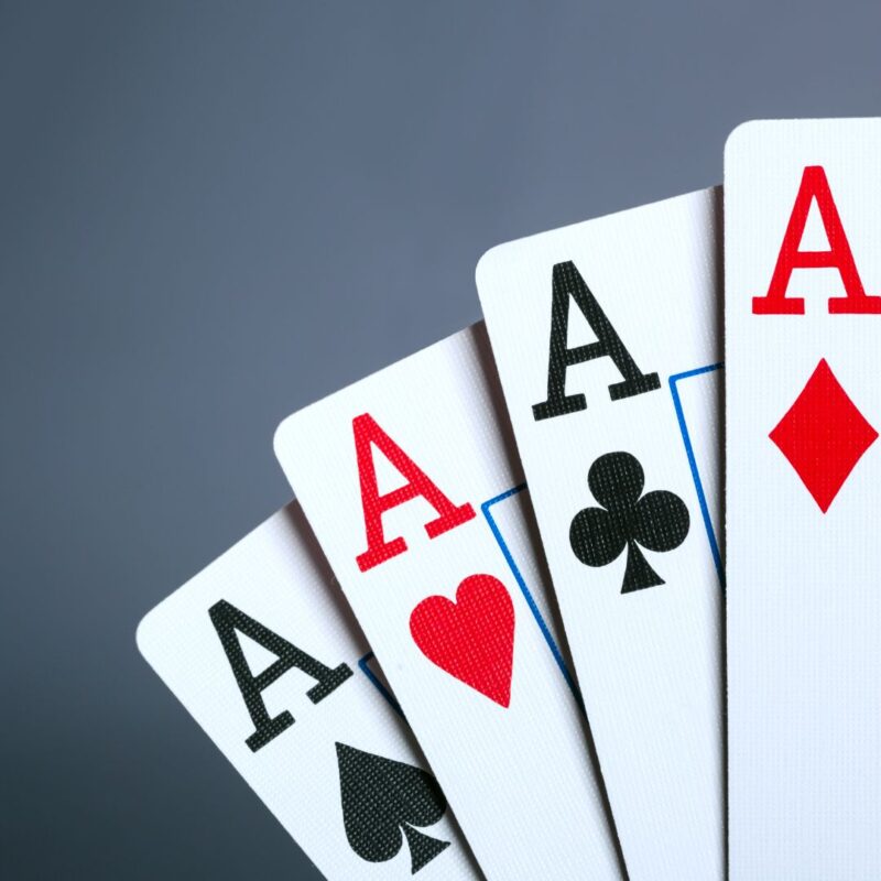 A fanned set of four playing cards, each showing an Ace from a different suit
