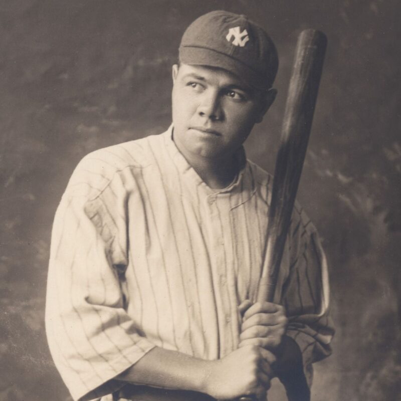 Babe Ruth wearing a New York Yankees baseball uniform and cap, holding a bat