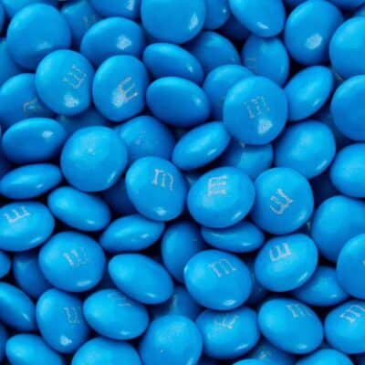 Close-up of several blue M&Ms with the signature "m" logo on each candy surface
