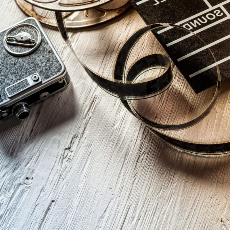 Vintage camera, film reel, and clapperboard on a rustic wooden surface