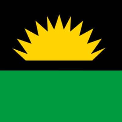 Flag of the Republic of Benin with a black top half featuring a yellow sunburst and a solid green bottom half