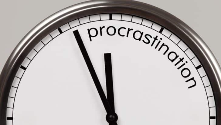 Close-up of a clock with the word 'procrastination' replacing numbers