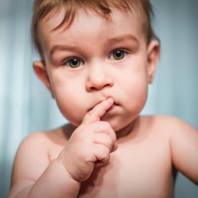 Curious baby with finger on lips looking forward