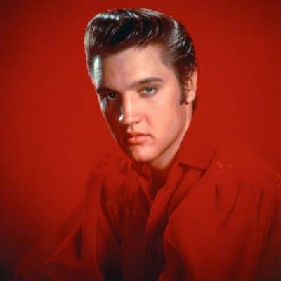 Elvis Presley wearing a red shirt against a red background