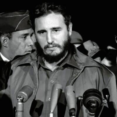 Fidel Castro speaking at microphones, surrounded by officials