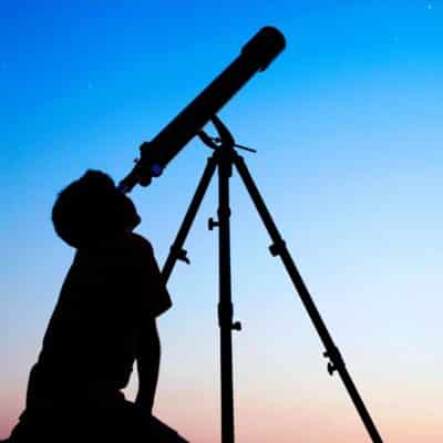 Silhouette of a person peering through a telescope at twilight, observing asteroid 2 Pallas