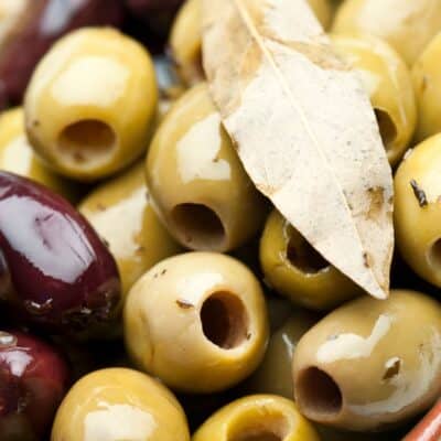 Close-up of pitted green and black olives with a bay leaf on top