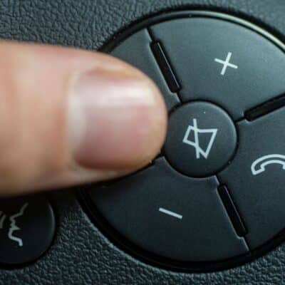 Finger pressing volume button on a car steering wheel control