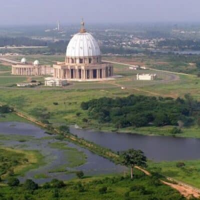 Large domed basilica surrounded by greenery and a small lake in Ivory Coast