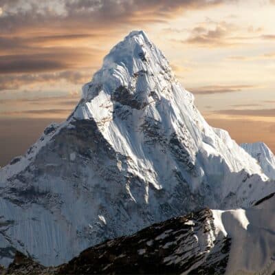 A snow-covered Mount Everest with a dramatic sunset backdrop