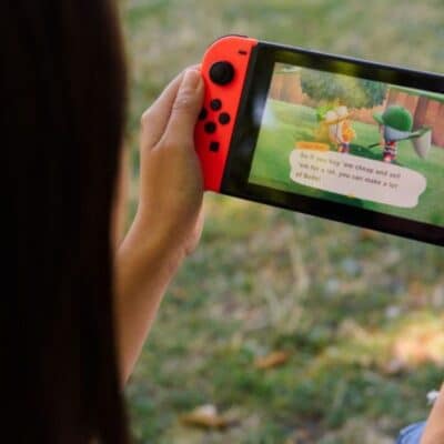 Person playing Animal Crossing on a Nintendo Switch outdoors