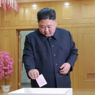 Kim Jong-un casting a ballot in a wooden-paneled voting room