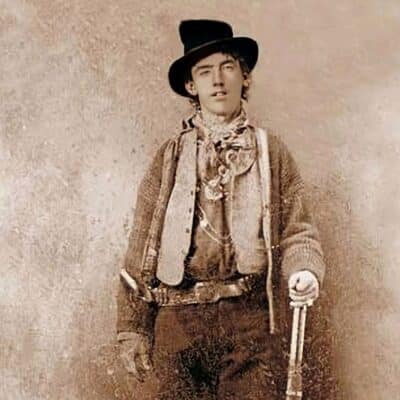 Young man in Old West attire holding a rifle and wearing a hat