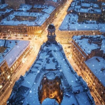 Snow-covered rooftops and streets in St. Petersburg during snowfall at dusk