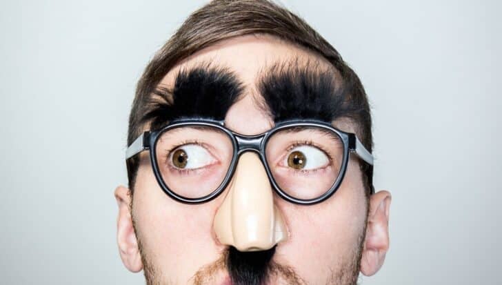 Person wearing a disguise with exaggerated glasses, eyebrows, and nose, illustrating quick identity swaps by CIA agents