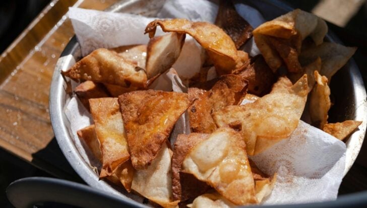 A bowl of crispy fresh tortilla chips on a paper towel